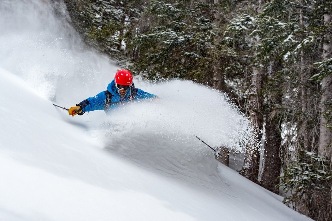 A skier carving hard and creating a cloud of snow.